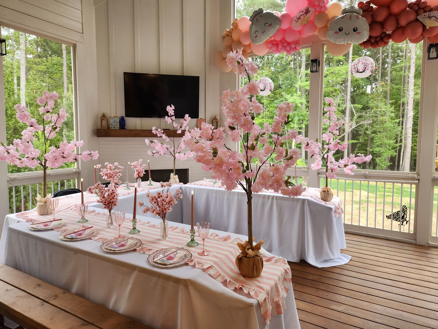 Cherry blossom tablescape with a blush striped runner, pink goblets and candles on a porch