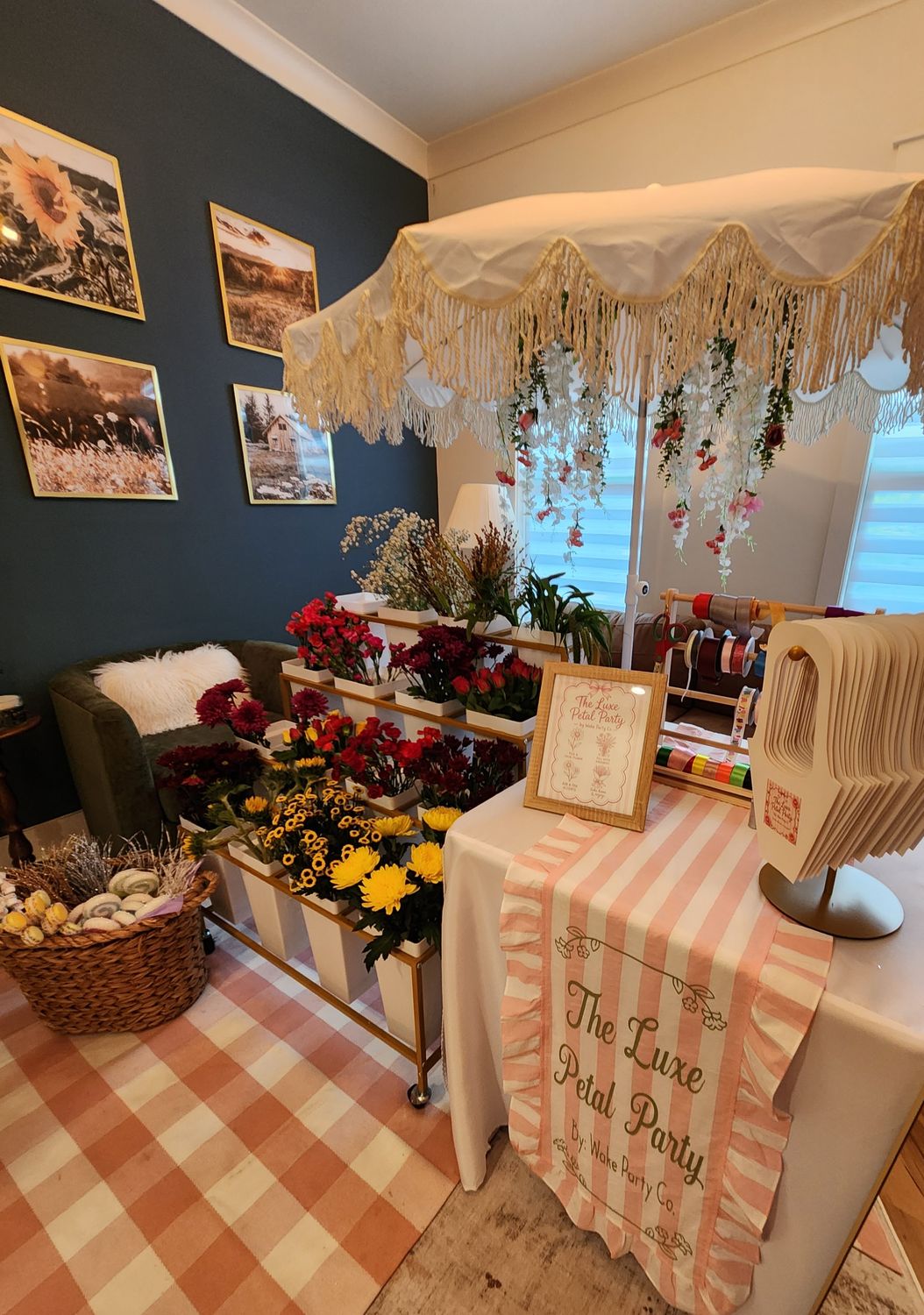 The Luxe Petal Party bloom bar with a fringed umbrella, buckets of fresh flowers and a branded striped runner