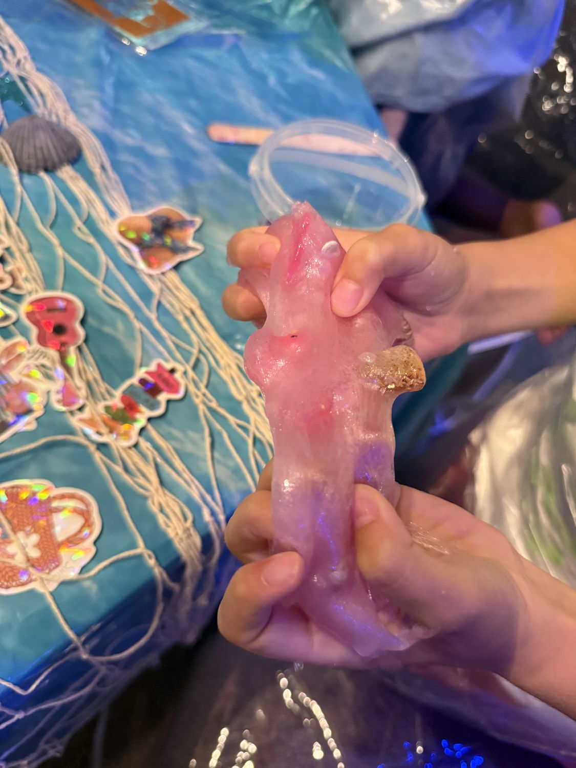 Hands holding pink slime with mermaid charms