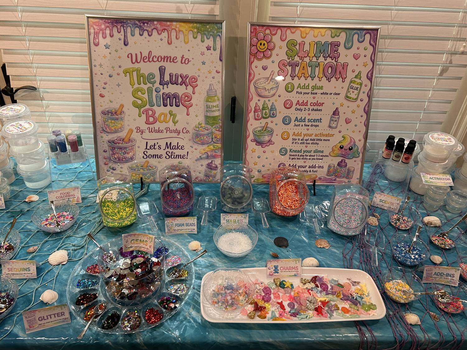 The Luxe Slime Bar station with jars of colorful add-ins, charms and signage