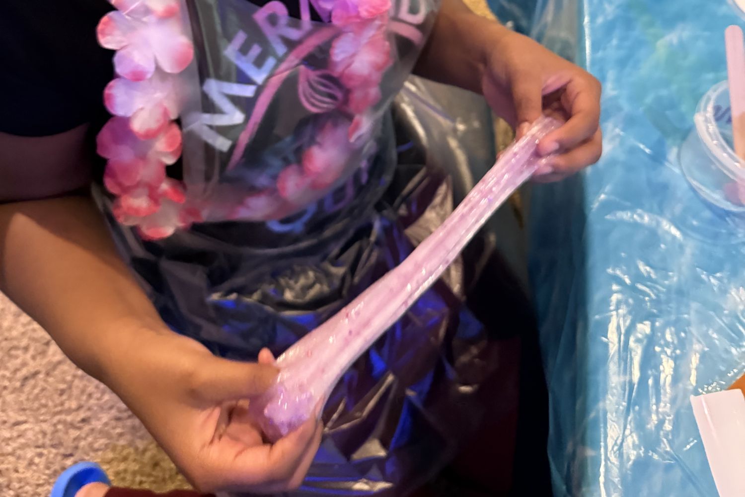 Hands stretching pink slime at the Luxe Slime Bar