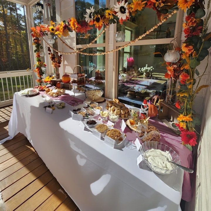 Fall buffet with pressed white linens and a sunflower garland on a screened porch in Wake Forest, NC