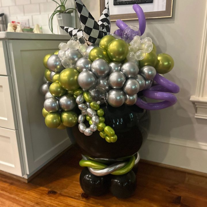 Halloween balloon cauldron with green and silver bubbling balloons and a witch hat topper