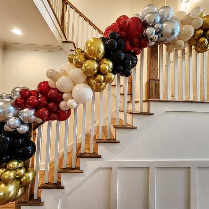 Burgundy, gold and silver organic balloon garland installed along a staircase in Wake Forest, NC