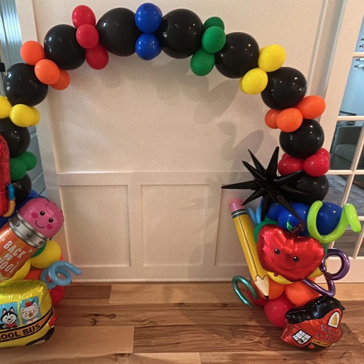Classic rainbow balloon arch with school-themed foil balloons