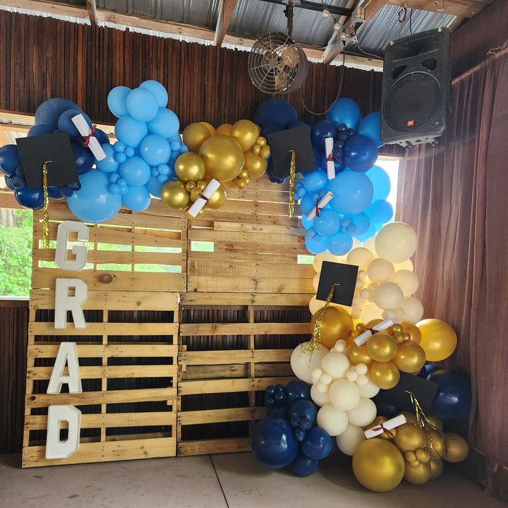 Custom graduation backdrop of wood pallets with GRAD letters and navy, blue and gold balloons in Raleigh, NC