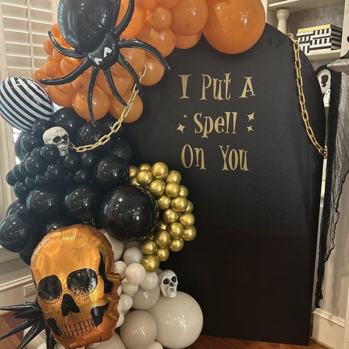 Halloween Effortless Arch with a black panel, gold lettering and an orange, black and gold balloon garland