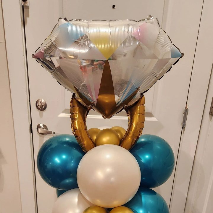 Teal, ivory and gold balloon column topped with a large diamond ring foil balloon